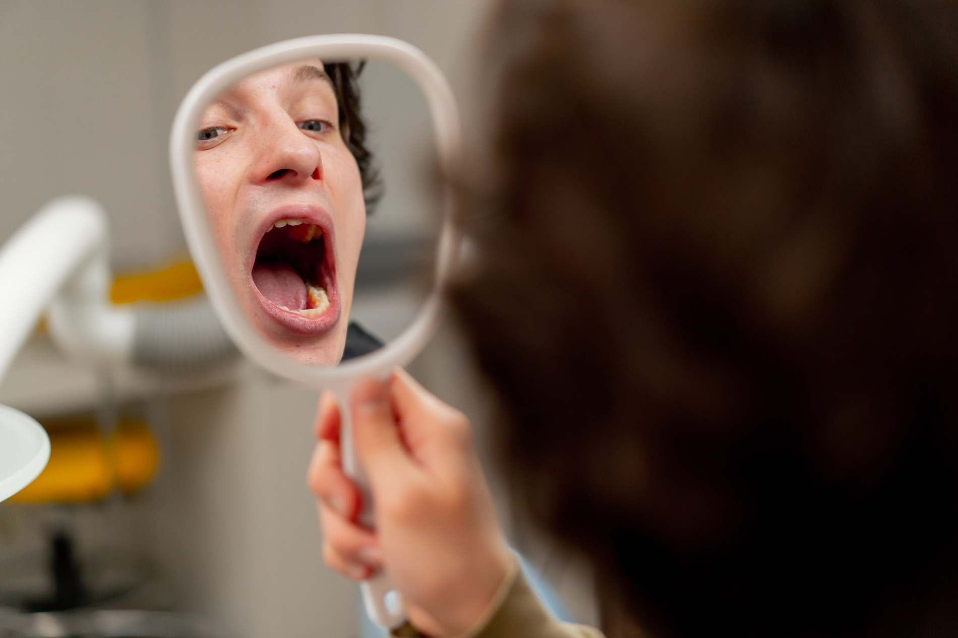 A woman looking at her teeth in a mirror