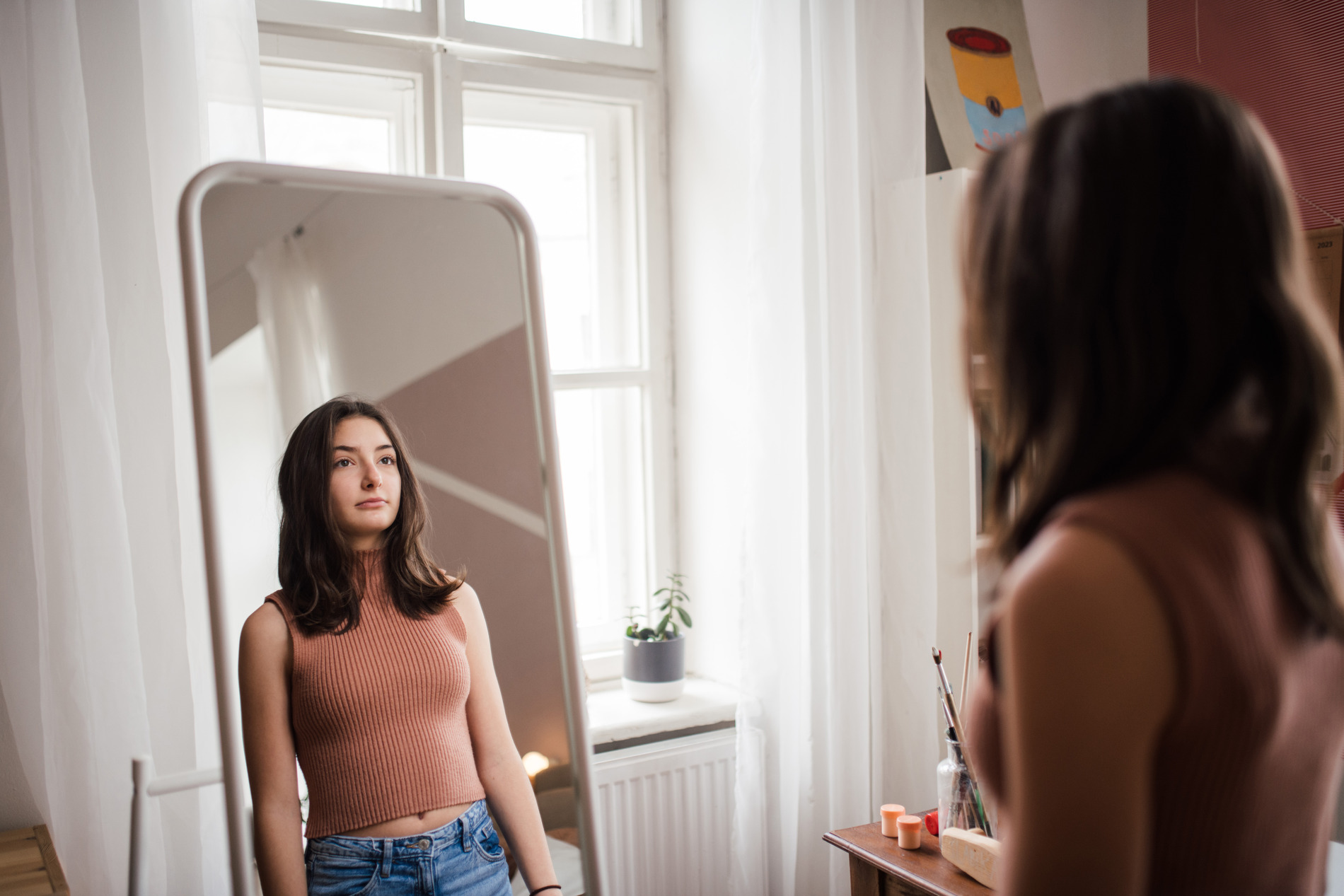 a girl looking at herself in the mirror