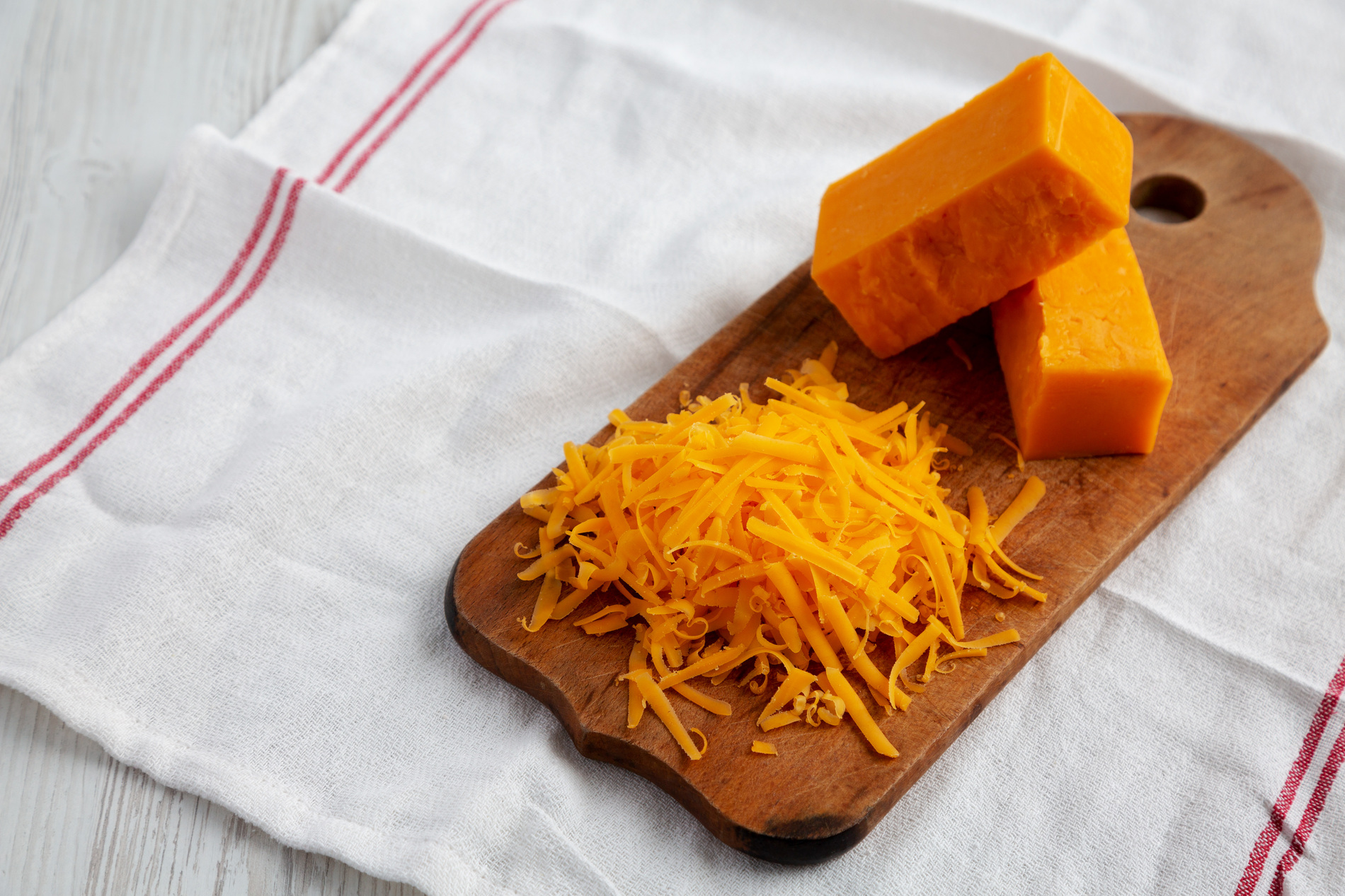 Shredded cheddar cheese on wooden board