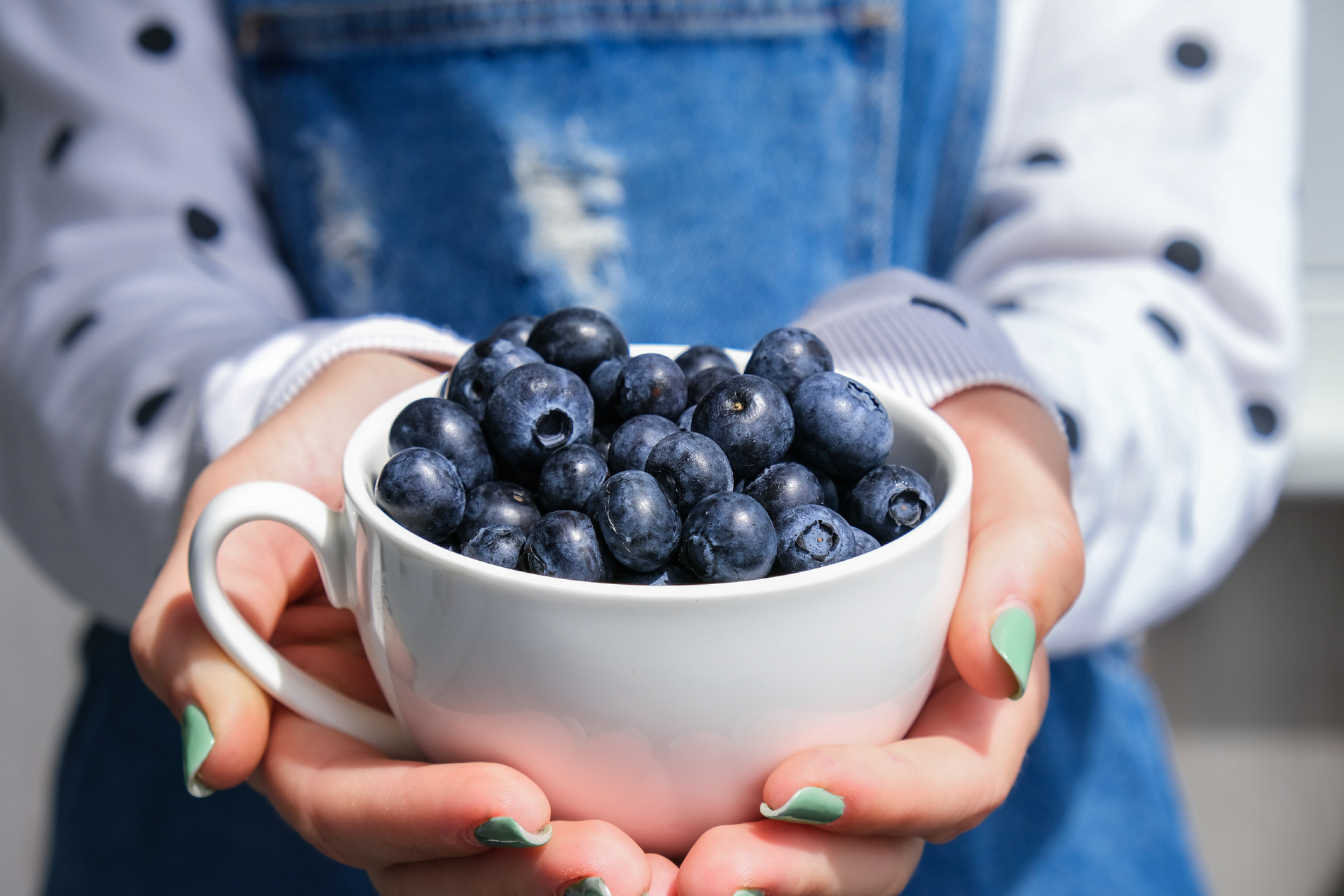 Woman holding bowl of fresh blueberries